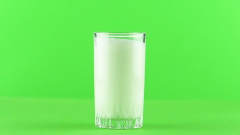Milk pouring into glass close up isolated on light green background Slow motion . Milk is holesome and natural product for healthy lifestyle