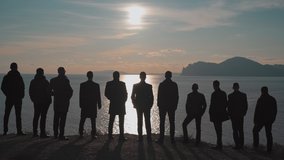 People in suits are standing by the sea in the backlight in Crimea