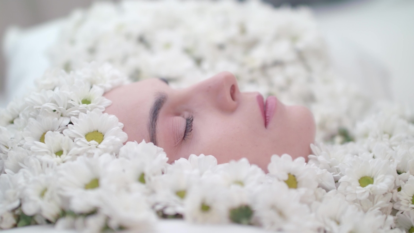 A woman sleeping in a pile of daisies and waking up from their fresh smell. Royalty-Free Stock Footage #1051518475