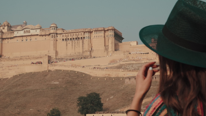 Back view of young beautiful woman tourist in hat while walking in old ancient amber fort. Travel Around the world concept
