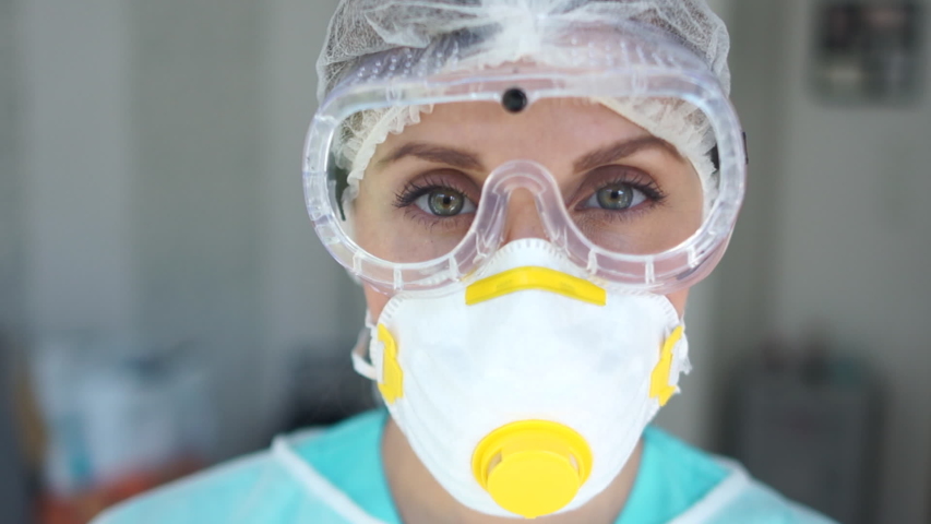 Female doctor during a coronavirus pandemic covid-19 takes off glasses and a protective mask, face marks are visible from the mask, red spots. Close portrait of a tired doctor | Shutterstock HD Video #1051525255
