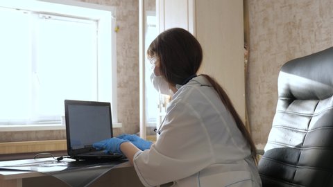 woman doctor in an office examines an x-ray of patient in hospital. doctor works in hospital office with laptop. Medical care and healthcare concept. coronovirus pandemic, pneumonia COVID-19 treatment
