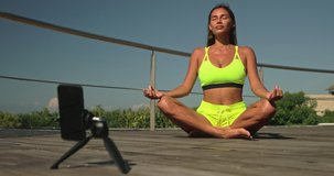 Beautiful girl record videos for subscribers of stomach vacuum yoga. Nauli kriya training for abdominal muscles. Young woman conducts online training during a pandemic. Self-isolation training online.