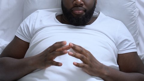 Nervous man drumming fingers lying in bed, erectile dysfunction, mans health