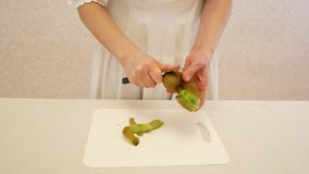 The girl brush with a knife the green kiwifruit. Tasty sweet fruit. 4k video.