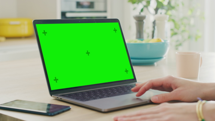 Close Up Green Screen Mock Up on a Laptop Computer. Device is Used on a Kitchen Table in a Modern Home. Person Uses Touch Pad and Presses Enter. Sunny Modern Kitchen with Healthy Lifestyle Vibes. Royalty-Free Stock Footage #1051549993