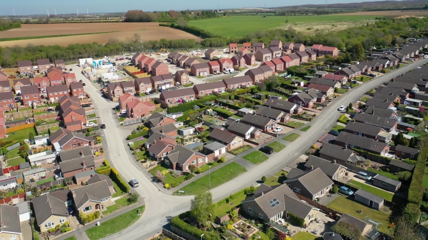 Aerial footage of a typical British housing  estate in the Village of Kippax in Leeds West Yorkshire, showing suburban housing estates, bungalows, road along side farmers fields the village. Royalty-Free Stock Footage #1051551175