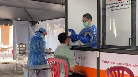 Melaka/Malaysia - May 1,2020 : A live view of real patient screening inside Covid 19 Mass Screening Area. A doctor taking history of patient and taking nasopharyngeal swab for Covid - 19 test