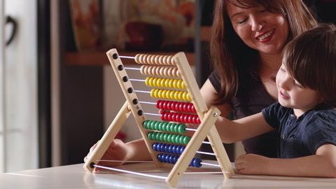 Mother and boy working mathematics with abacus in home.