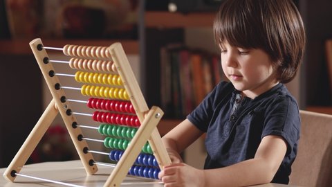 4K,Little boy working with abacus in home.