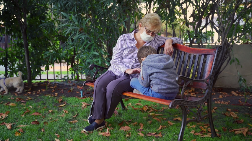 Grandmother playing games with her grandson in the back garden and wearing protective masks