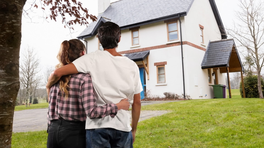 Animation of the rear view of a happy Caucasian couple embracing in the garden outside their house, home ownership concept, digital composite