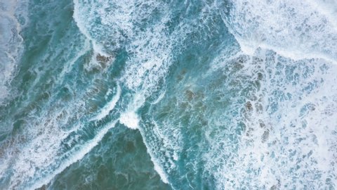 Beautiful ocean surf washes steep coastal cliffs covered with dense tropical greenery. Water is blue and clear, it boils at the feet of the rocks. Aerial footage, view from above. 4K