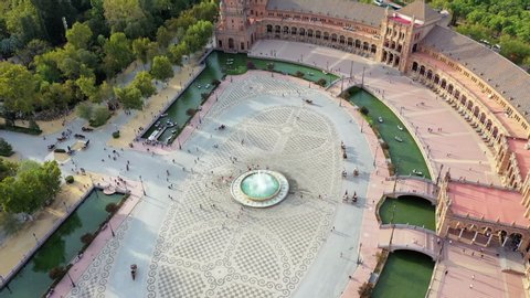 Aerial panning shot of people around fountain at famous plaza in city, drone flying forward over tourists at Plaza de Espana - Seville, Spain