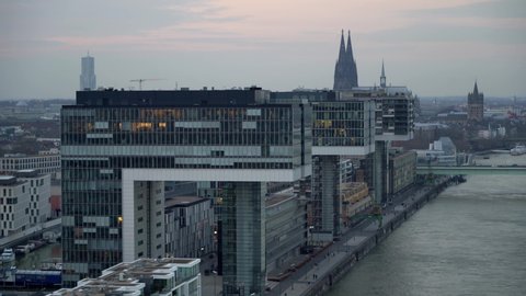 Aerial Drone Shot of modern Office Buildings with Glass front next to a river with the skyline and cathedral of cologne in the background at sunset.