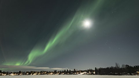  Video of brilliant green Aurora shining over Swedish frozen lake and winter landscape, light rays from a full moon in different soft colors, moving camera close up view, Northern Sweden, Lapland