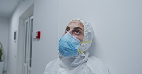 Dramatic video portrait of an exhausted nurse or physician praying while taking off the protection surgical face mask in the hospital during Covid-19 pandemia. Nurse taking off the face mask during