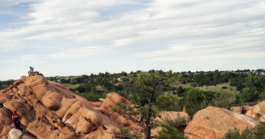 Time lapse panning shot of tourists on rock formation amidst trees at park against sky - Garden of the Gods, Colorado