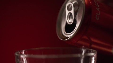 Moscow, Russia - 14 04 2020: coca cola began pouring in a glass with ice cubes on red background slow motion cinematic footage with cola bottle on background.
