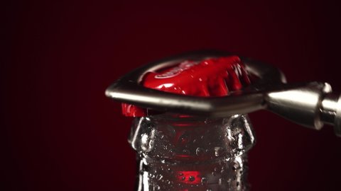 Moscow, Russia - 14 04 2020: Close up macro bottle red cap of coca cola open with gray opener on red background. Coca-cola bottle with droplets of water.