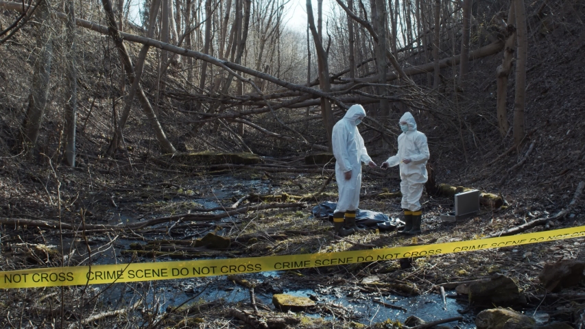 Forensic specialist working in the forest. Police criminalists collecting evidence and making criminal investigation. Crime scene. | Shutterstock HD Video #1051600393