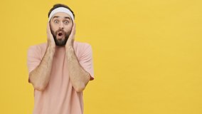 A surprised young athletic man in sportswear is doing a winner gesture isolated over a yellow background in studio
