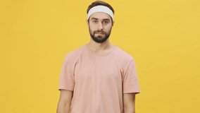 A handsome young athletic man in sportswear is showing OK gesture isolated over a yellow background in studio
