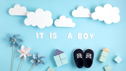 Cute newborn baby boy shoes with festive decoration over blue background. Baby shower, birthday, invitation or greeting card idea. Stop motion animation
