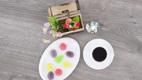 Coffee cup with candies and wooden box on wooden table background.