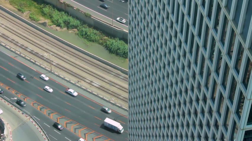 Cinemagraph of traffic on Ayalon highway from Azrieli tower view in Tel Aviv. A bus travels on the road in a loop. A high angle from inside one of the three buildings.