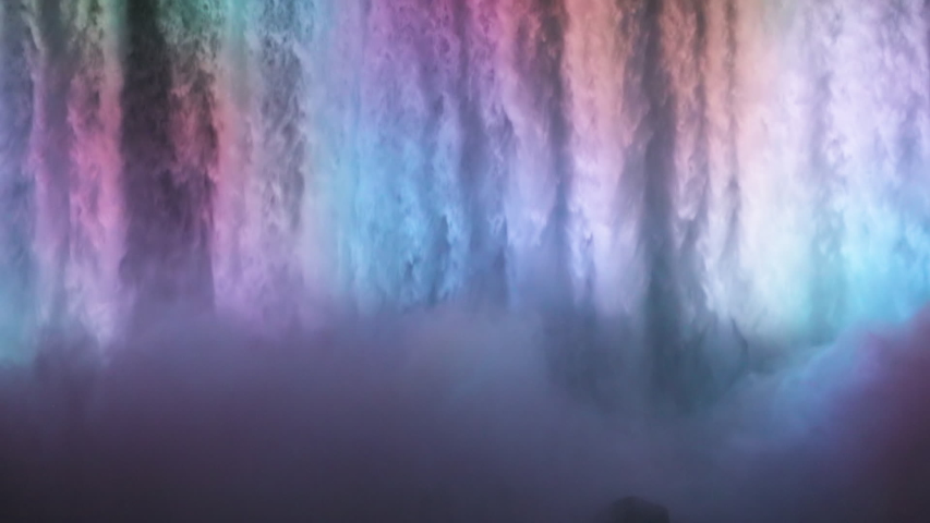 NIAGARA FALLS, NEW YORK - 8 AUG 2019: Niagara Falls night water multi colored lights waterfall slowt. International border USA New York and Canadian province Ontario. honeymoon vacation destination.