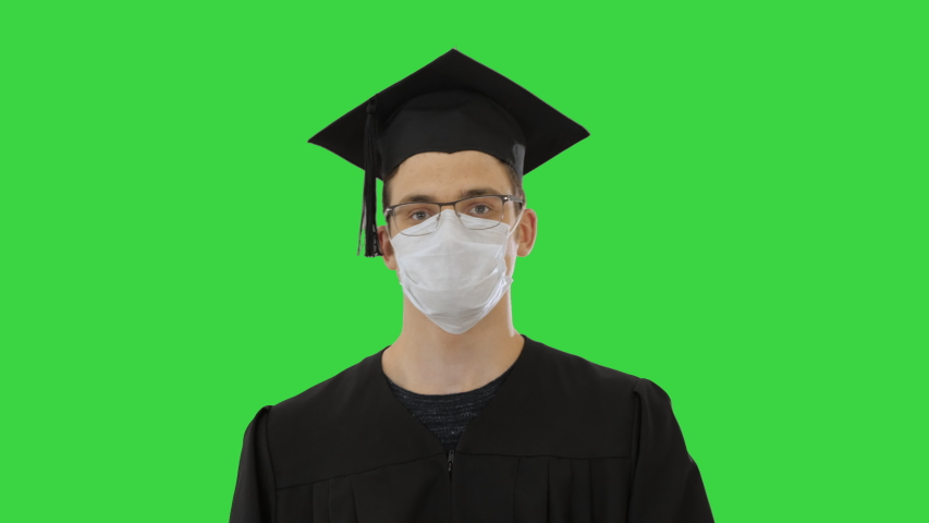 Graduate student in a medical mask walking on a Green Screen, Chroma Key.