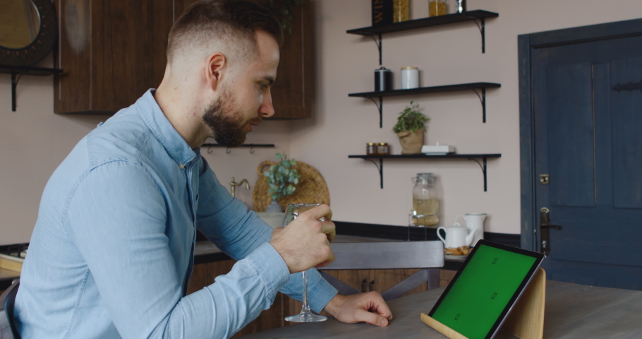 GREEN SCREEN CHROMA KEY Cucasian Hispanic man having a glass of wine during video call. Stay home, quarantine life