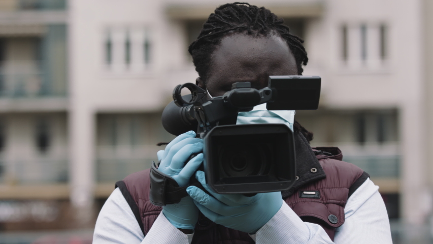 african cameraman recording with professional camera. Reporting about covid-19 outbreak. Royalty-Free Stock Footage #1051640059