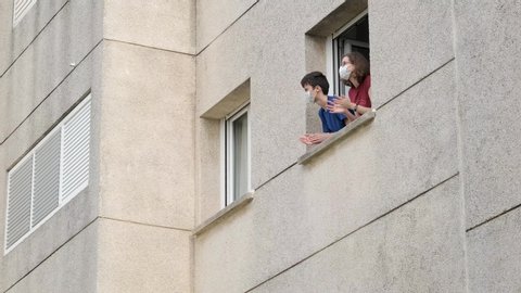 Caucasian people in medical mask applauding in window from apartment. Family supporting of medical staff, health workers, Coronavirus pandemic in Europe, Spain, Italy. People clapping hands. 4k video.