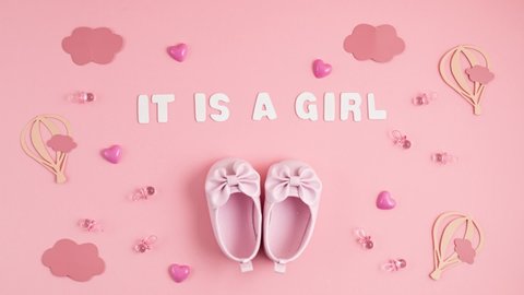 Cute newborn baby girl shoes with festive decoration over pink background. Baby shower, birthday, invitation or greeting card idea. Stop motion animation