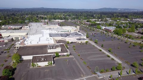 Aerial bird's eye view flyover of Clackamas Town Center shopping mall near Portland Oregon during the coronavirus COVID-19 pandemic with thousands of empty parking spots in the parking lot.