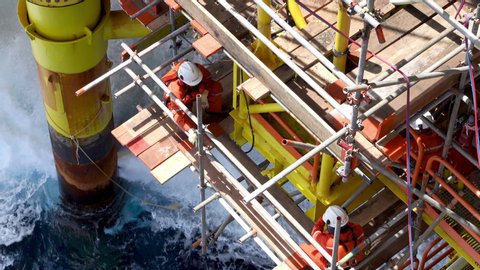 KELANTAN, MALAYSIA - AUG 14th 2019 : Offshore workers with Personal Protective Equipment (PPE) and floating devices working below oil and gas platform nearby caisson pipeline for maintenance works.