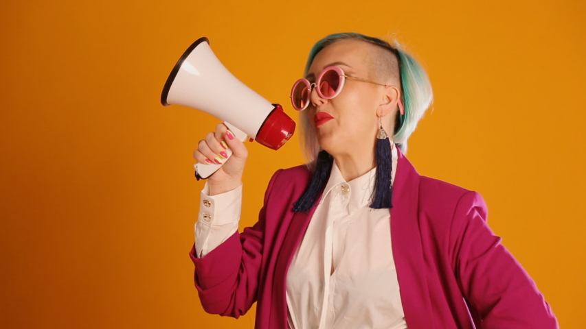 A girl on a yellow background shouts into a megaphone to announce something. 