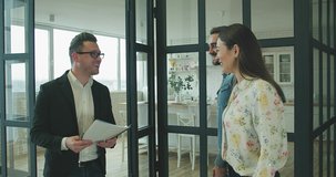 Happy Couple with real-estate agent visiting house for sale or for rent, Young man and woman cheerful at home. Loving people buying an apartment. Immovables market 4K slow motion video.
