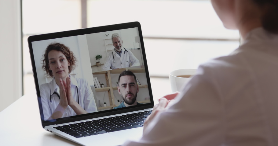 Female nurse participating young and old doctors team videoconference on laptop screen. Medic workers group conference video calling in healthcare elearning webcam training. Over shoulder closeup view Royalty-Free Stock Footage #1051686094