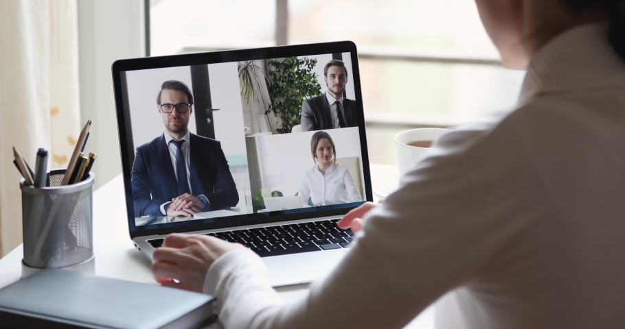 Over shoulder closeup view of business woman videoconferencing partners team by online video call virtual app. Remote worker conferencing colleagues group on pc laptop screen working from home office. Royalty-Free Stock Footage #1051686097