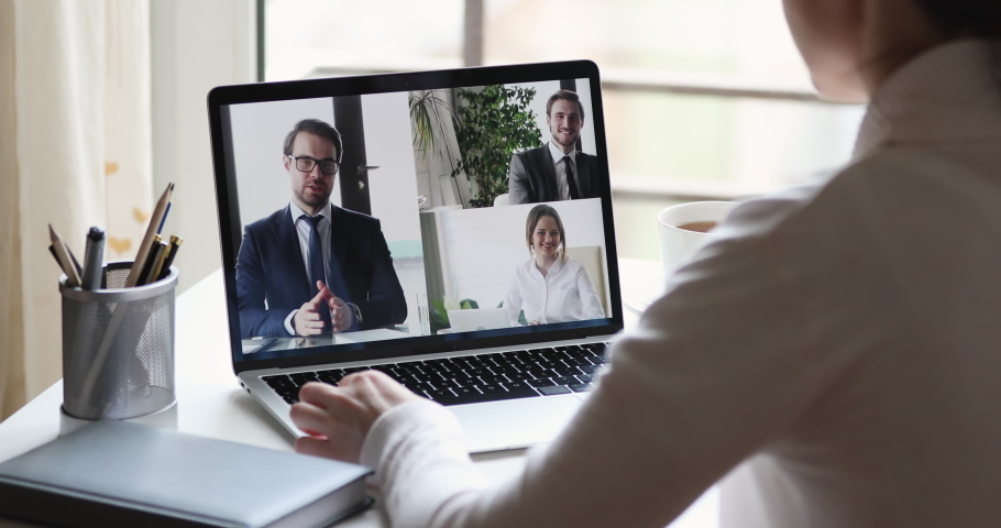 Over shoulder closeup view of business woman videoconferencing partners team by online video call virtual app. Remote worker conferencing colleagues group on pc laptop screen working from home office. Royalty-Free Stock Footage #1051686097