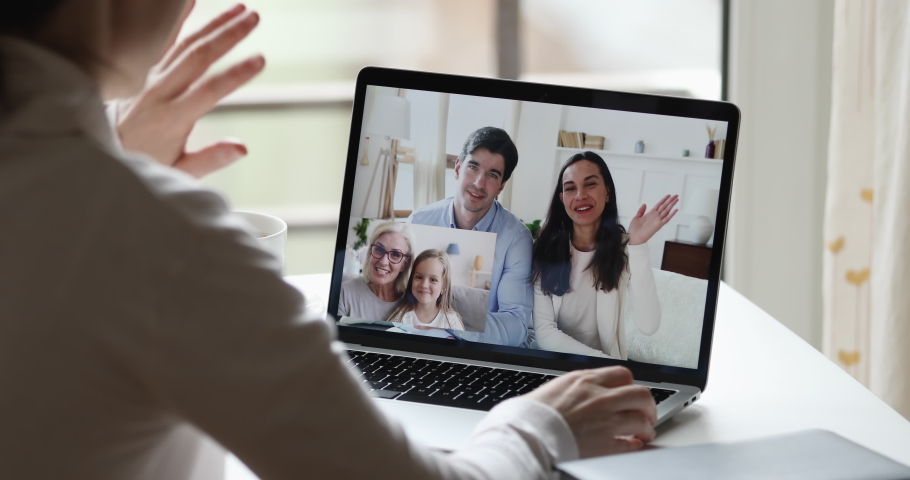 Young woman waving hand video calling long distance relatives by web cam. Happy big family chatting in conference group chat during social quarantine concept. Over shoulder closeup laptop screen view Royalty-Free Stock Footage #1051686100