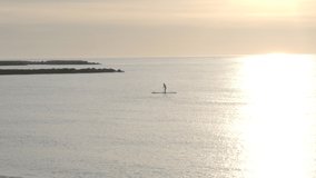 Man practicing paddle surf during sunrise at sea. Concept: sport and adventure