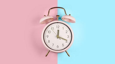 Ringing twin bell vintage classic alarm clock Isolated on blue and pink pastel colorful trendy background.