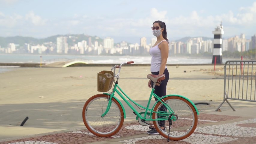 Happy positive girl, beautiful woman on the beach with face mask with her bike. Happy end quarantine and home isolation. Victory over coronavirus. Pandemic Covid-19.
 Royalty-Free Stock Footage #1051699567