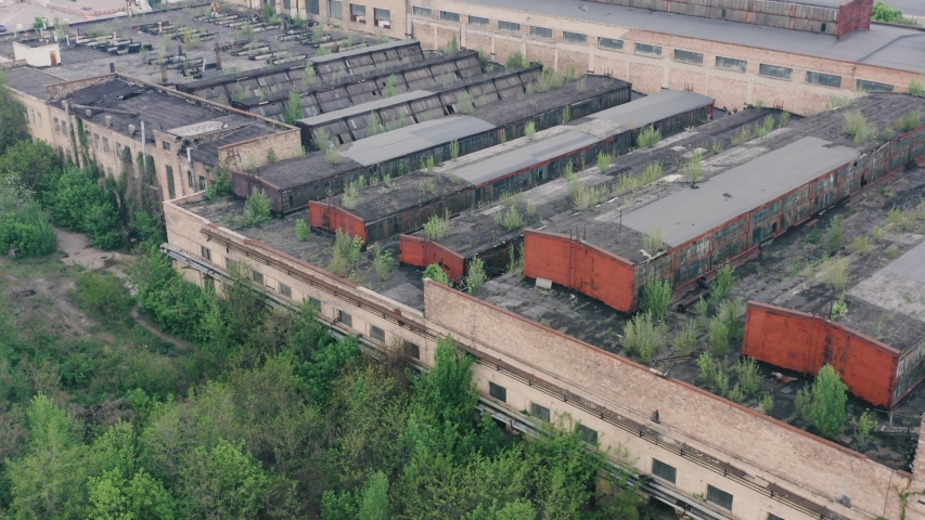 Aerial view of the production workshop an old abandoned big factory with the territory overgrown with greenery