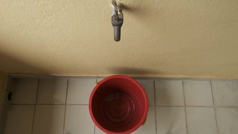 A top down footage of man open tap and water been filled in the bucket for floor cleaning.