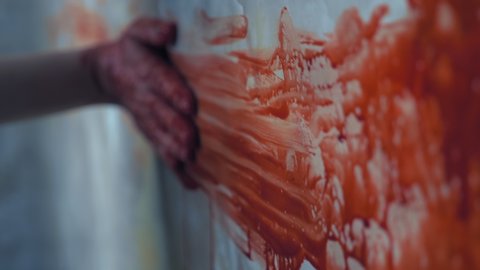 a female hand reaches out, holding on to the wall, leaving a trace of blood on the wall.